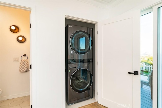 clothes washing area featuring stacked washer and dryer, baseboards, laundry area, and ornamental molding