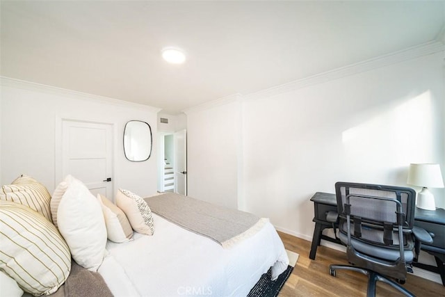 bedroom with baseboards, wood finished floors, and ornamental molding