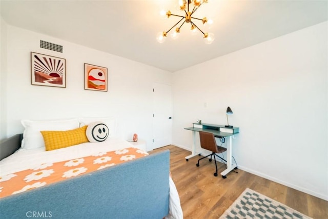 bedroom featuring an inviting chandelier, wood finished floors, visible vents, and baseboards