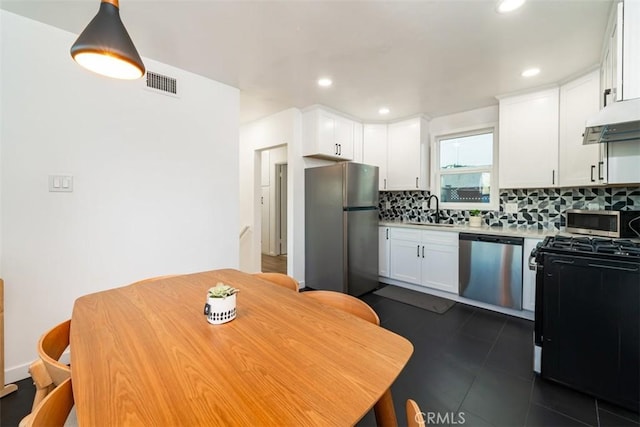 kitchen with stainless steel appliances, backsplash, visible vents, a sink, and white cabinetry