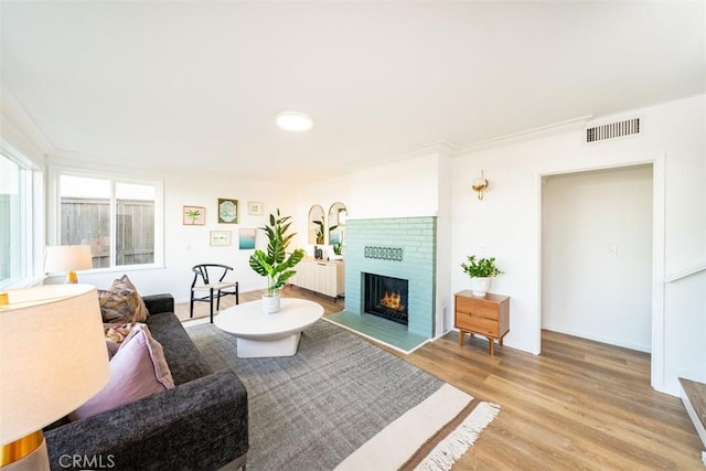living area with light wood-type flooring, visible vents, and a fireplace