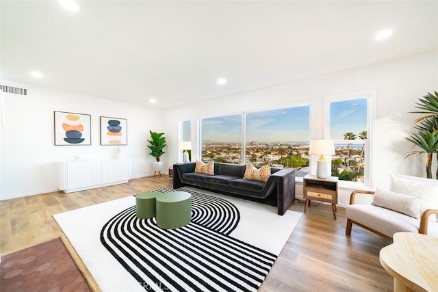 living room with wood finished floors, visible vents, recessed lighting, and radiator