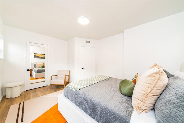 bedroom featuring baseboards, wood finished floors, and visible vents