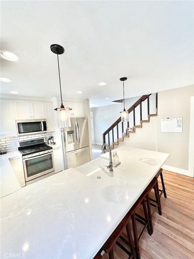 82 Avalon Terrace Rd, Avalon, CA 90704 - kitchen with a sink, decorative backsplash, light wood-type flooring, white cabinets, and appliances with stainless steel finishes