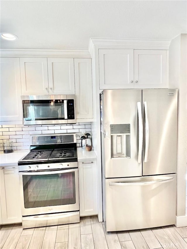 82 Avalon Terrace Rd, Avalon, CA 90704 - kitchen featuring white cabinets, decorative backsplash, light countertops, wood finish floors, and appliances with stainless steel finishes