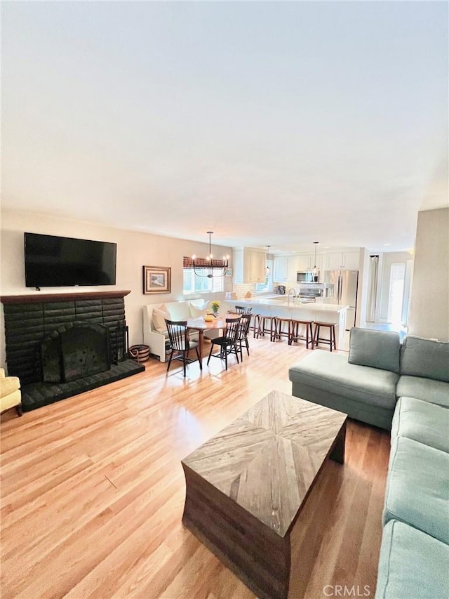 82 Avalon Terrace Rd, Avalon, CA 90704 - living area featuring a stone fireplace, light wood finished floors, and an inviting chandelier
