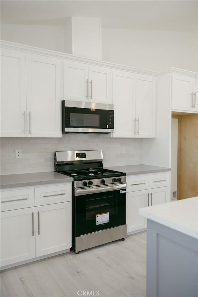 7452 Chase Ave, Hesperia, CA 92345 - kitchen featuring stainless steel appliances, white cabinetry, decorative backsplash, light countertops, and light wood-type flooring