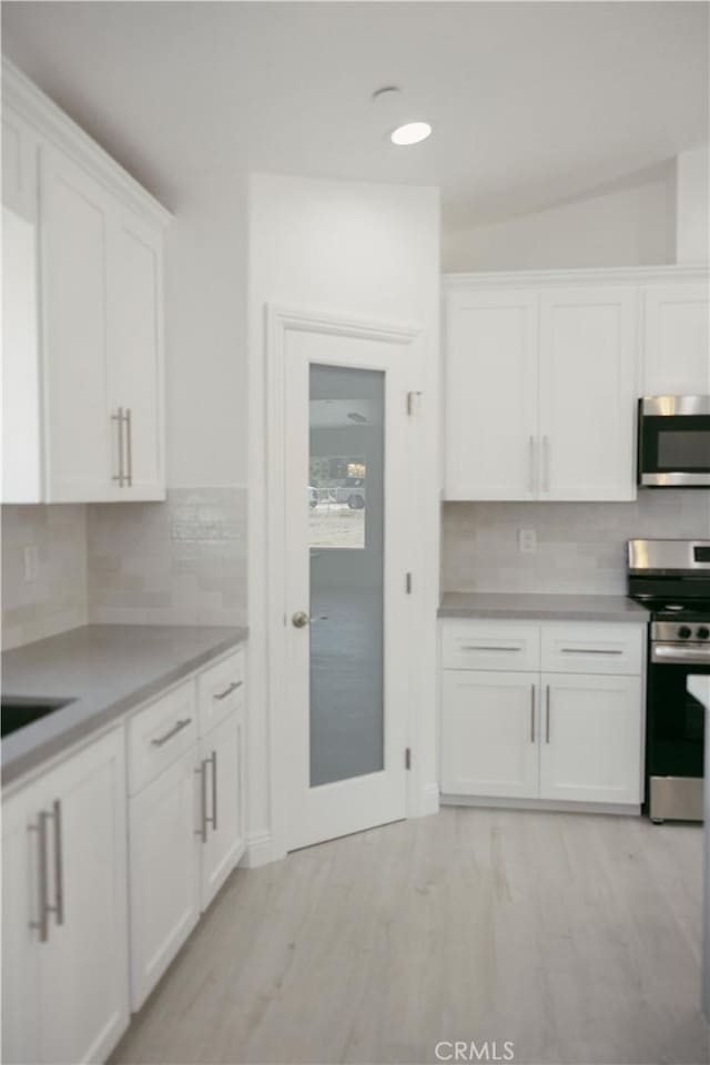 7452 Chase Ave, Hesperia, CA 92345 - kitchen with stainless steel appliances, white cabinets, light wood-style flooring, decorative backsplash, and recessed lighting