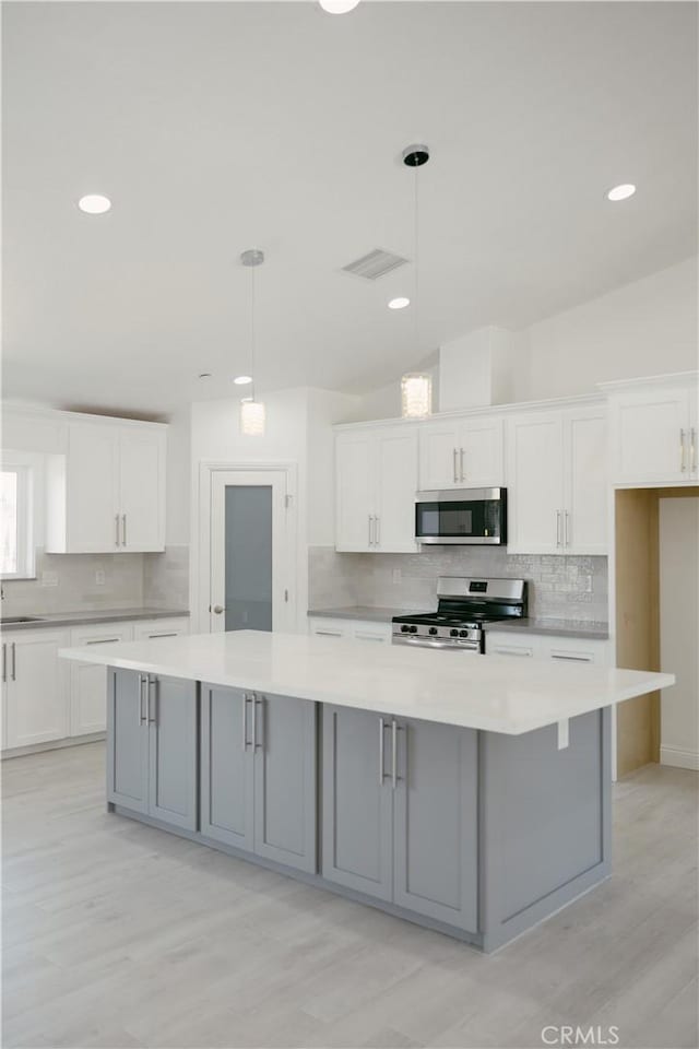 7452 Chase Ave, Hesperia, CA 92345 - kitchen with appliances with stainless steel finishes, decorative backsplash, white cabinets, light countertops, and light wood finished floors