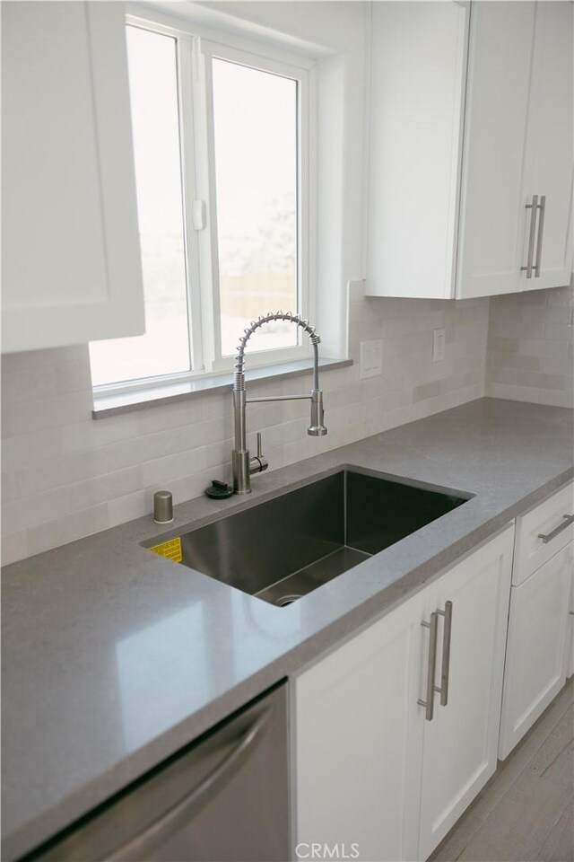 7452 Chase Ave, Hesperia, CA 92345 - kitchen featuring backsplash, a sink, dishwasher, white cabinetry, and light countertops