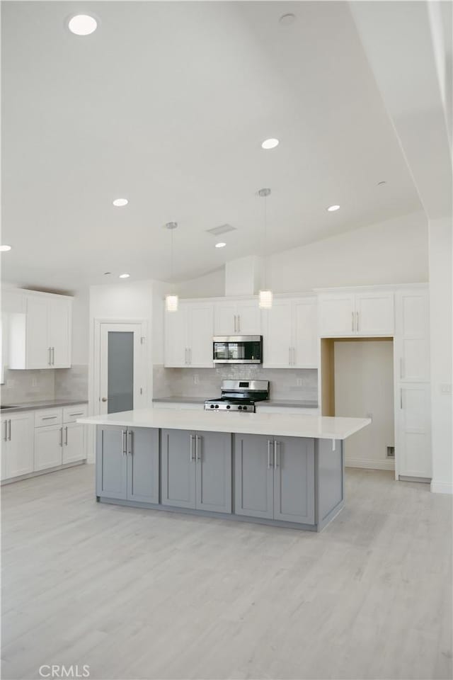 7452 Chase Ave, Hesperia, CA 92345 - kitchen with stainless steel appliances, tasteful backsplash, white cabinetry, light wood-style flooring, and vaulted ceiling