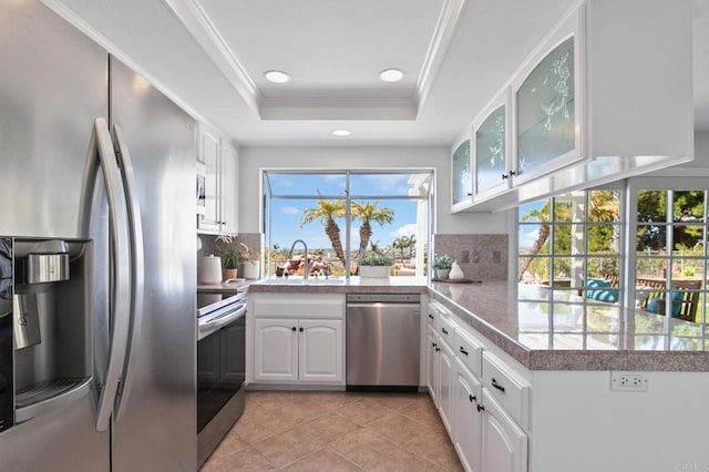 kitchen featuring tasteful backsplash, a sink, glass insert cabinets, stainless steel appliances, and white cabinets