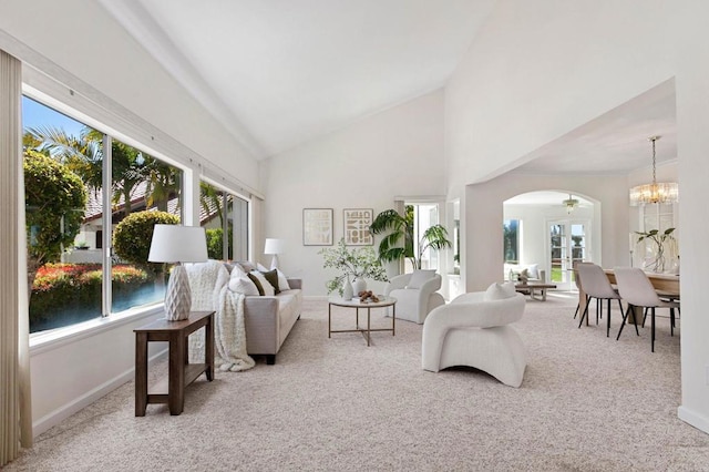 living room with arched walkways, carpet floors, a notable chandelier, and high vaulted ceiling
