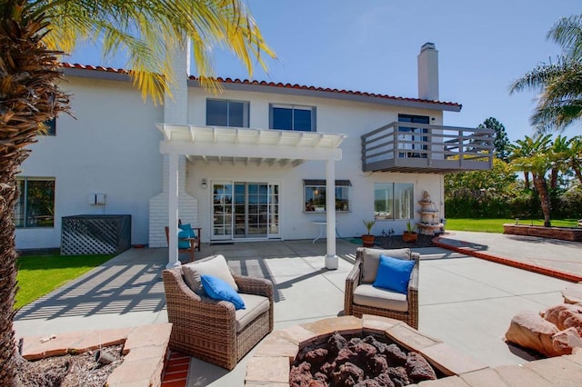 back of house with a chimney, a patio area, a balcony, and stucco siding