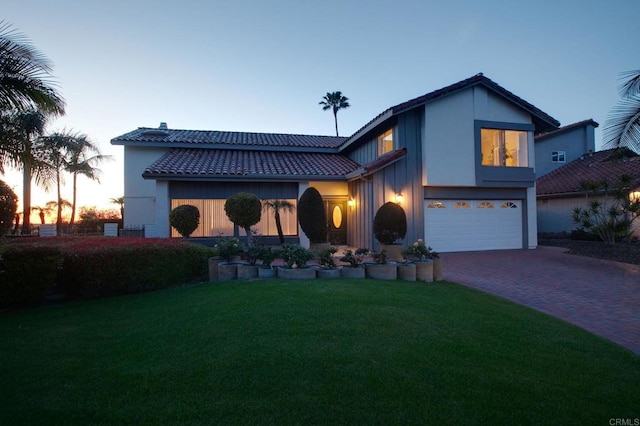 mediterranean / spanish-style home with a tile roof, a front lawn, driveway, a garage, and stucco siding