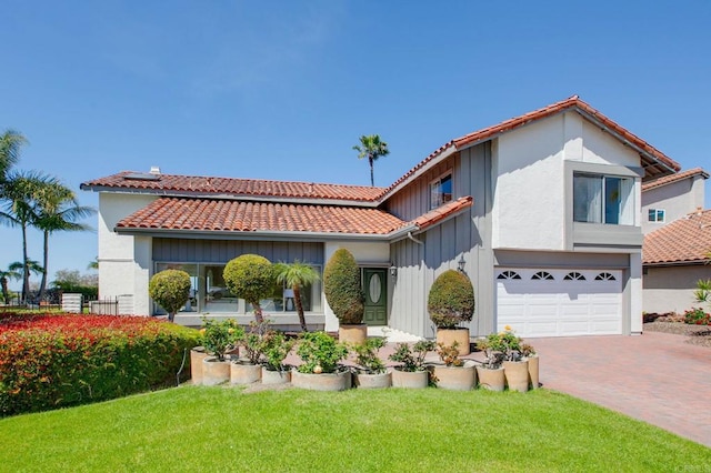 mediterranean / spanish-style house with a tiled roof, a garage, board and batten siding, a front yard, and decorative driveway