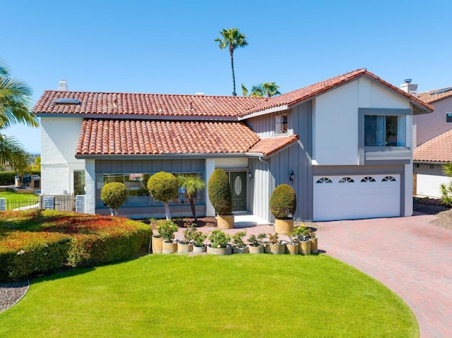 mediterranean / spanish home featuring a tiled roof, an attached garage, board and batten siding, decorative driveway, and a front yard
