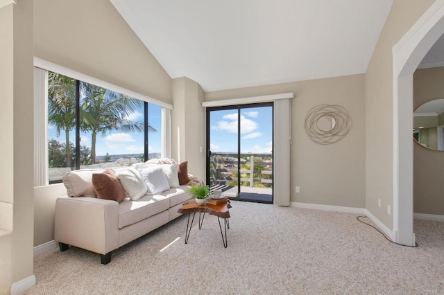 carpeted living room with arched walkways, vaulted ceiling, and baseboards