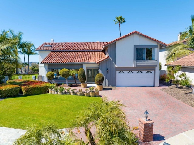 mediterranean / spanish-style house with a front lawn, an attached garage, a tiled roof, and stucco siding