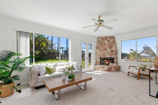 carpeted living room with a fireplace, ceiling fan, baseboards, and ornamental molding