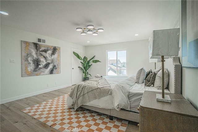 bedroom with recessed lighting, wood finished floors, visible vents, baseboards, and a notable chandelier