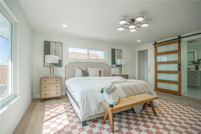 bedroom featuring a barn door, a closet, light wood-type flooring, a notable chandelier, and recessed lighting