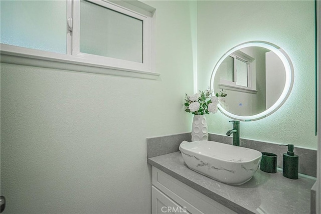 bathroom with a textured wall and vanity