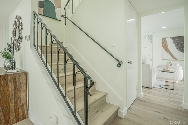 stairs with baseboards, wood finished floors, and recessed lighting