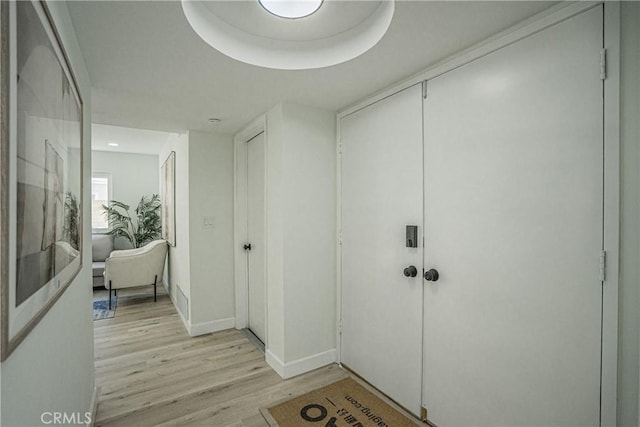 corridor featuring light wood-style flooring and baseboards