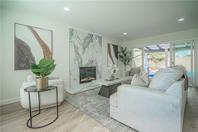living room with wood finished floors, recessed lighting, and a high end fireplace