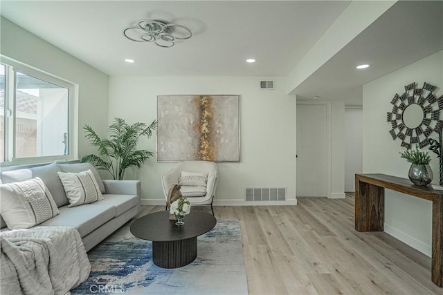 living area featuring baseboards, visible vents, and light wood-style floors