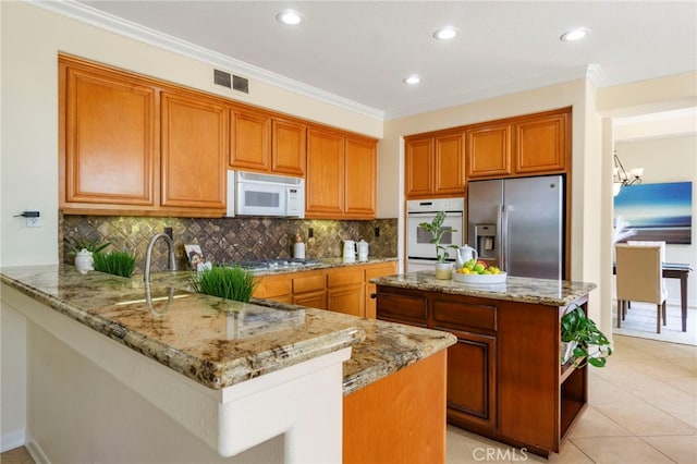 20904 Parkside, Lake Forest, CA 92630 - kitchen with stainless steel appliances, brown cabinetry, light stone countertops, a chandelier, and crown molding