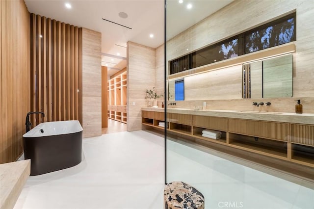 full bath with a freestanding tub, a sink, double vanity, and recessed lighting