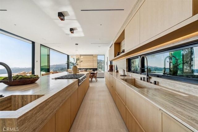 kitchen featuring stainless steel gas stovetop, modern cabinets, a sink, and light stone counters