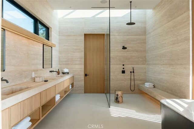 bathroom featuring concrete floors, double vanity, walk in shower, and a sink