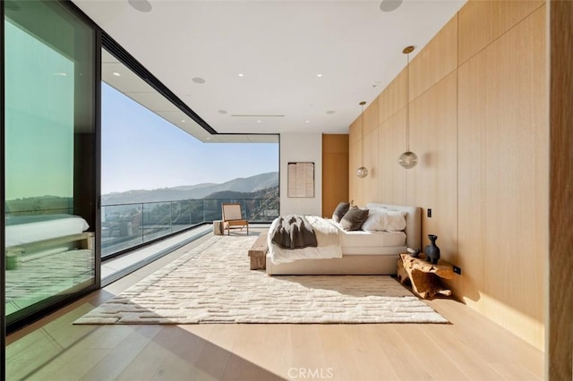 bedroom featuring a wall of windows, a mountain view, and wood finished floors