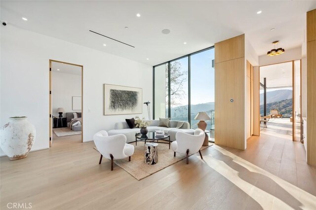 living room featuring light wood-style flooring, floor to ceiling windows, recessed lighting, and a mountain view