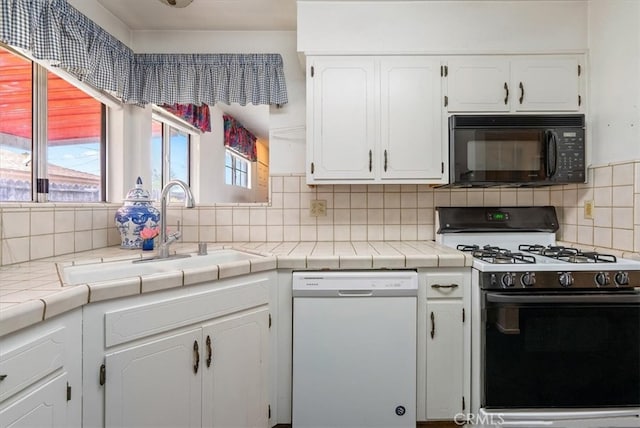 kitchen featuring white cabinets, black microwave, range with gas stovetop, and white dishwasher