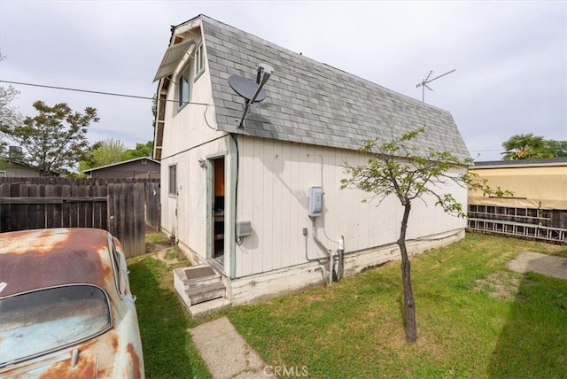 view of side of property with a lawn, roof with shingles, and fence