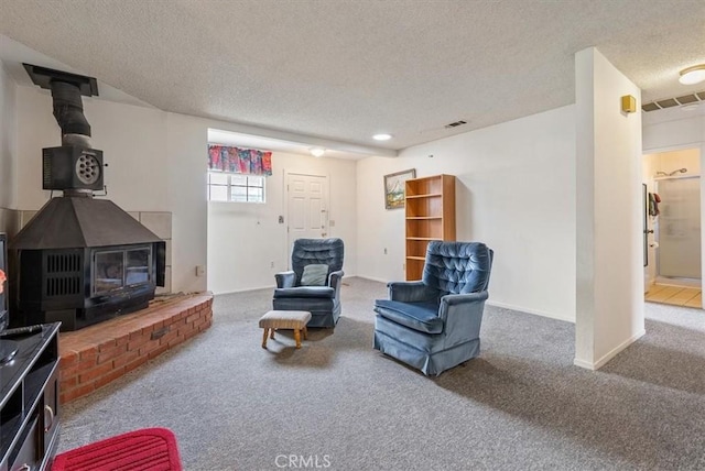 living area with visible vents, carpet flooring, a textured ceiling, and a wood stove