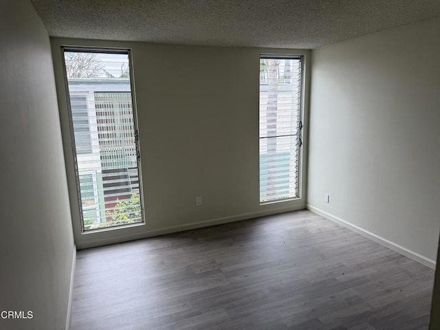 3700 Dean Dr Unit 3306, Ventura, CA 93003 - empty room featuring wood finished floors, a textured ceiling, and plenty of natural light