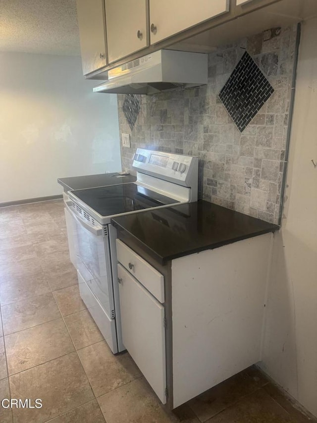 3700 Dean Dr Unit 3306, Ventura, CA 93003 - kitchen with white electric stove, white cabinets, tasteful backsplash, dark countertops, and under cabinet range hood