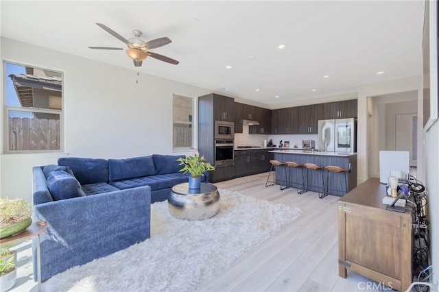 living room featuring recessed lighting, light wood-type flooring, a ceiling fan, and a toaster