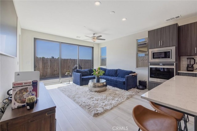 living room with ceiling fan, light wood-style floors, visible vents, and recessed lighting