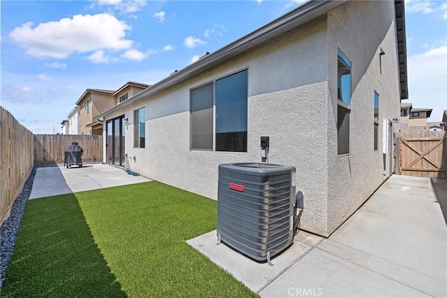 rear view of property featuring a fenced backyard, central AC unit, a lawn, a patio, and stucco siding