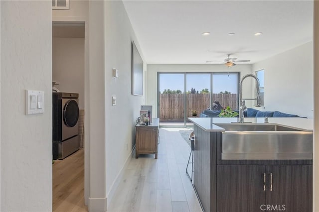 kitchen featuring ceiling fan, a sink, visible vents, and light wood-type flooring