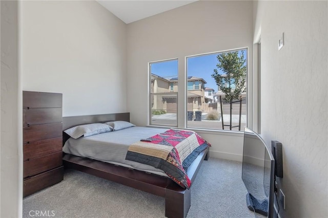 carpeted bedroom featuring baseboards and multiple windows