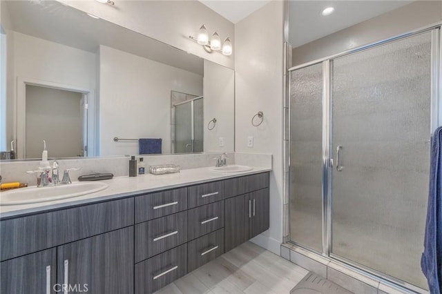 full bathroom with a sink, double vanity, and a stall shower