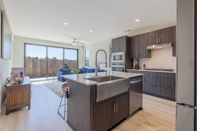 kitchen featuring under cabinet range hood, appliances with stainless steel finishes, a sink, and light countertops