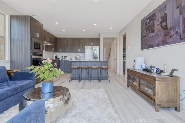 living room with visible vents, light wood finished floors, and recessed lighting